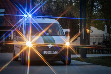 Mavi ve sarı ışıklı bir polis minibüsü, dramatik bir vurgu için yıldız patlaması etkisi yaratarak alacakaranlıkta olay yerini aydınlatıyor. 10.05.2025 Valmiera, Letonya
