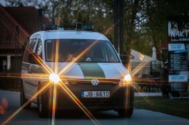 Mavi ve sarı ışıklı bir polis minibüsü, dramatik bir vurgu için yıldız patlaması etkisi yaratarak alacakaranlıkta olay yerini aydınlatıyor. 10.05.2025 Valmiera, Letonya