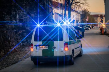 Mavi ve sarı ışıklı bir polis minibüsü, dramatik bir vurgu için yıldız patlaması etkisi yaratarak alacakaranlıkta olay yerini aydınlatıyor. 10.05.2025 Valmiera, Letonya