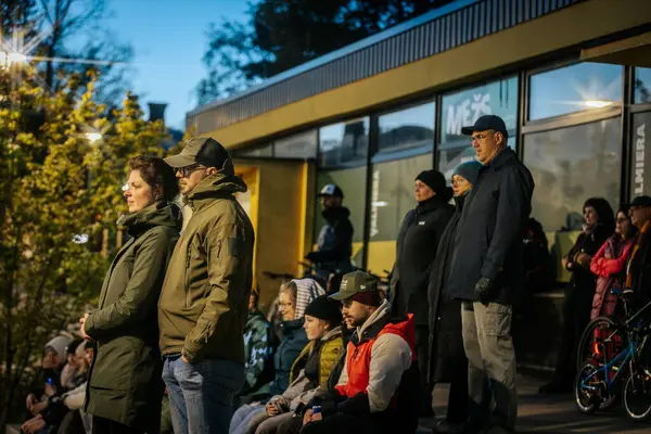 İnsanlar Kino Pedalis festivali sırasında ön planda tanıtım pankartıyla merdivenlerde oturup açık hava film gösterimi izliyor. 10.05.2025 Valmiera, Letonya