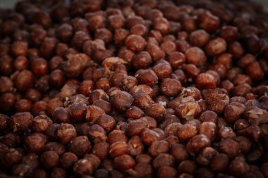 Kurumuş bezelyelerle dolu bir kâsenin ayrıntılı bir görüntüsü kaba dokusunu ve toprak rengini gözler önüne seriyor, doğal gıda ve tarım görselleri için ideal..