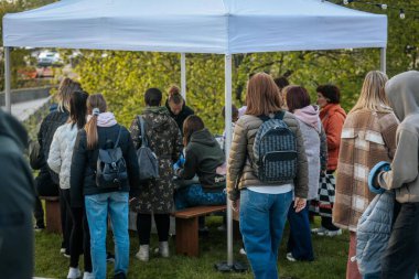 İnsanlar, el yapımı eşyalar, yerel yiyecekler ve el sanatları sunan bir açık hava pazarındaki teçhizat çadırlarının altındaki 17.05.2025 Valmiera, Letonya