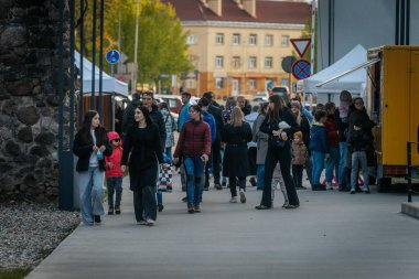 İnsanlar, el yapımı eşyalar, yerel yiyecekler ve el sanatları sunan bir açık hava pazarındaki teçhizat çadırlarının altındaki 17.05.2025 Valmiera, Letonya