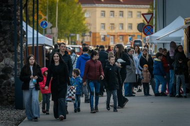 İnsanlar, el yapımı eşyalar, yerel yiyecekler ve el sanatları sunan bir açık hava pazarındaki teçhizat çadırlarının altındaki 17.05.2025 Valmiera, Letonya