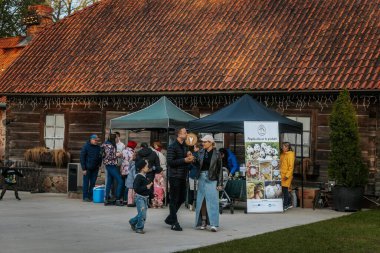 İnsanlar, el yapımı eşyalar, yerel yiyecekler ve el sanatları sunan bir açık hava pazarındaki teçhizat çadırlarının altındaki 17.05.2025 Valmiera, Letonya