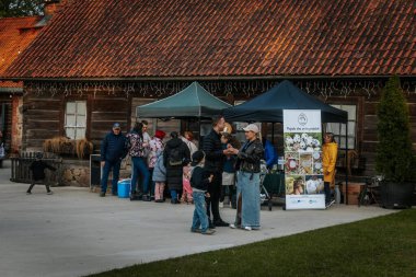 İnsanlar, el yapımı eşyalar, yerel yiyecekler ve el sanatları sunan bir açık hava pazarındaki teçhizat çadırlarının altındaki 17.05.2025 Valmiera, Letonya