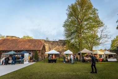 İnsanlar, el yapımı eşyalar, yerel yiyecekler ve el sanatları sunan bir açık hava pazarındaki teçhizat çadırlarının altındaki 17.05.2025 Valmiera, Letonya