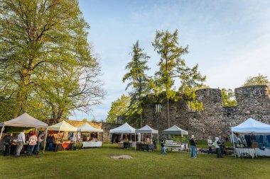 İnsanlar, el yapımı eşyalar, yerel yiyecekler ve el sanatları sunan bir açık hava pazarındaki teçhizat çadırlarının altındaki 17.05.2025 Valmiera, Letonya