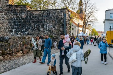 İnsanlar, el yapımı eşyalar, yerel yiyecekler ve el sanatları sunan bir açık hava pazarındaki teçhizat çadırlarının altındaki 17.05.2025 Valmiera, Letonya