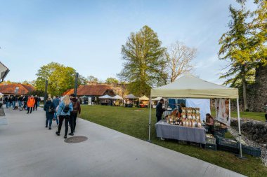 İnsanlar, el yapımı eşyalar, yerel yiyecekler ve el sanatları sunan bir açık hava pazarındaki teçhizat çadırlarının altındaki 17.05.2025 Valmiera, Letonya