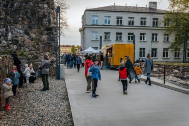 İnsanlar, el yapımı eşyalar, yerel yiyecekler ve el sanatları sunan bir açık hava pazarındaki teçhizat çadırlarının altındaki 17.05.2025 Valmiera, Letonya