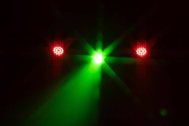 Bir sıra kırmızı LED sahne ışığı ve tek bir parlak yeşil spot ışığı karanlığı kesiyor. Dramatik ve şenlikli bir atmosfer yaratır. Kopyalama alanı dahil.