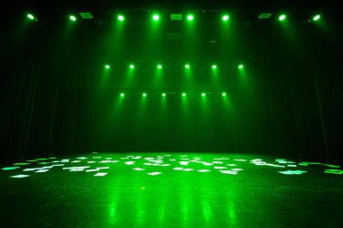 Sönük bir sahne yeşil ışıkla yıkanmış, kağıtlar yere saçılmış. Perdeleri ve sahne ışıkları olan dramatik bir atmosfer. Kopyalama alanı dahil.