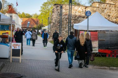 İnsanlar, el yapımı eşyalar, yerel yiyecekler ve el sanatları sunan bir açık hava pazarındaki teçhizat çadırlarının altındaki 17.05.2025 Valmiera, Letonya