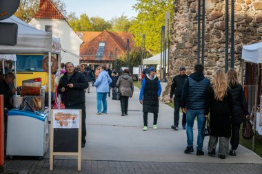 İnsanlar, el yapımı eşyalar, yerel yiyecekler ve el sanatları sunan bir açık hava pazarındaki teçhizat çadırlarının altındaki 17.05.2025 Valmiera, Letonya