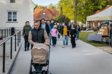 İnsanlar, el yapımı eşyalar, yerel yiyecekler ve el sanatları sunan bir açık hava pazarındaki teçhizat çadırlarının altındaki 17.05.2025 Valmiera, Letonya