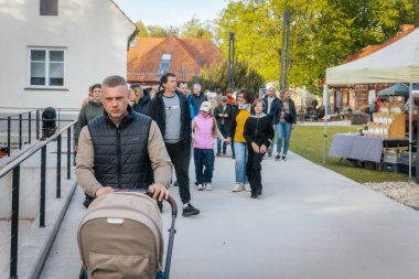 İnsanlar, el yapımı eşyalar, yerel yiyecekler ve el sanatları sunan bir açık hava pazarındaki teçhizat çadırlarının altındaki 17.05.2025 Valmiera, Letonya