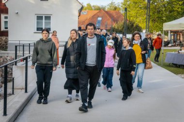 İnsanlar, el yapımı eşyalar, yerel yiyecekler ve el sanatları sunan bir açık hava pazarındaki teçhizat çadırlarının altındaki 17.05.2025 Valmiera, Letonya