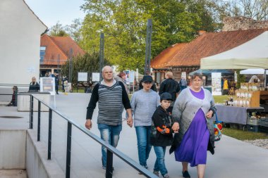 İnsanlar, el yapımı eşyalar, yerel yiyecekler ve el sanatları sunan bir açık hava pazarındaki teçhizat çadırlarının altındaki 17.05.2025 Valmiera, Letonya