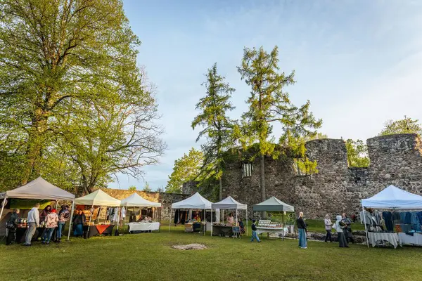 İnsanlar, el yapımı eşyalar, yerel yiyecekler ve el sanatları sunan bir açık hava pazarındaki teçhizat çadırlarının altındaki 17.05.2025 Valmiera, Letonya