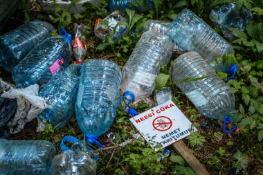 Letonya 'da çöp atmamak için uyarıda bulunan bir işaret, ormanda plastik şişeler ve çöplerle çevrili yerde yatıyor. 18.05.2025 Valmiera, Letonya