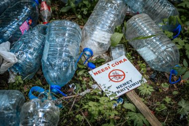 Letonya 'da çöp atmamak için uyarıda bulunan bir işaret, ormanda plastik şişeler ve çöplerle çevrili yerde yatıyor. 18.05.2025 Valmiera, Letonya