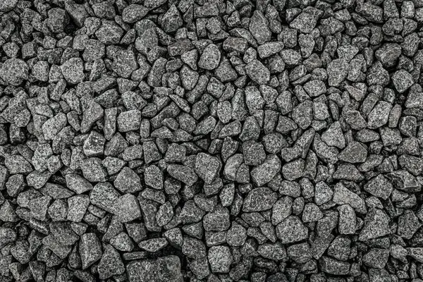 Gri tonlarda ve çeşitli boyutlarda sıkıştırılmış ezilmiş çakıl taşlarının yüksek çözünürlüklü üst görüntüsü, detaylı kaya dokusu ve doğal deseni göstermektedir..