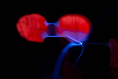 Çarpıcı bir plazma küresi, çekirdeğinden parlak mavi ve pembe elektrik yayları yayarak, karanlıkta büyüleyici ve renkli bir statik enerji gösterisi yaratır..