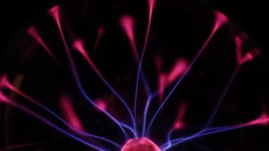 Çarpıcı bir plazma küresi, çekirdeğinden parlak mavi ve pembe elektrik yayları yayarak, karanlıkta büyüleyici ve renkli bir statik enerji gösterisi yaratır..