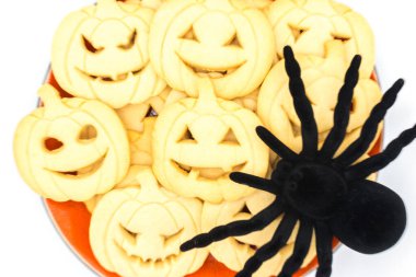 Cadılar Bayramı 'nda kabak şeklinde kurabiyeler ve beyaz arka planda izole edilmiş bir örümceğin üst görüntüsü..