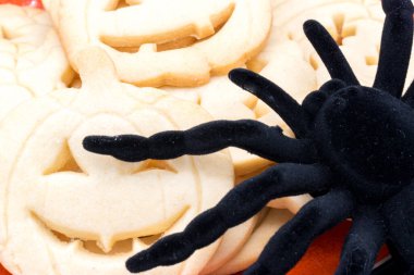 Cadılar Bayramı balkabağı şeklinde kurabiyeler ve bir örümcek.