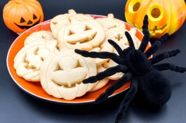 Cadılar Bayramı balkabağı şekilli kurabiyeler, oyuncak bir örümcek ve biraz cadılar bayramı süsü..