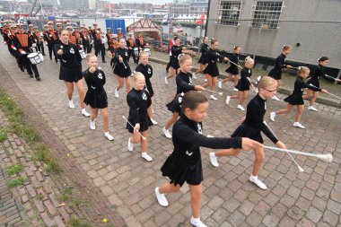 Little girl majorettes and brass band in a harbour festival