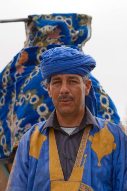man in traditional Moroccan costume with camel in the desert 
