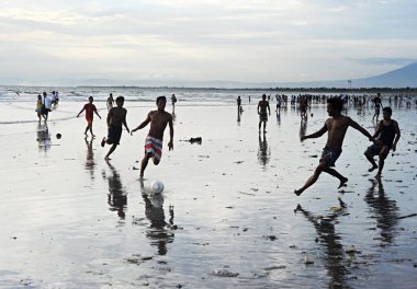 Sahilde futbol oynayan adam.