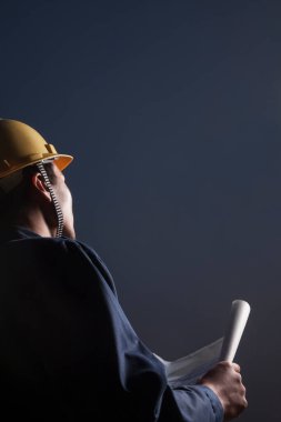 bir plan alacakaranlıkta, arka görünümü tutan bir kask içinde genç erkek mühendis