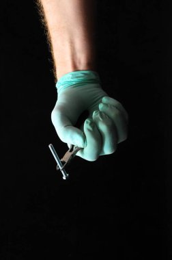 Siyah arka planda bir şırınga ile el.