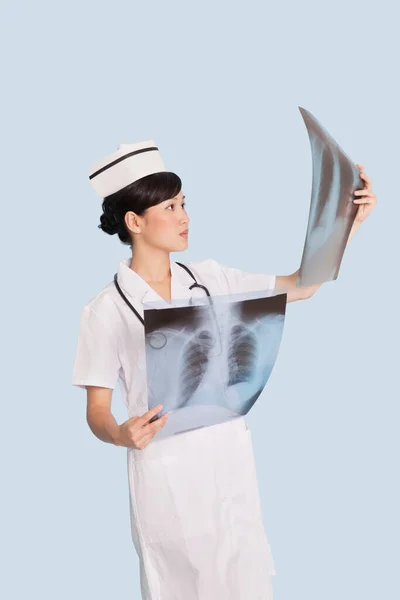 Kvinnliga Läkare Analysera Röntgen Rapporter Över Ljusblå Bakgrund — Stockfoto