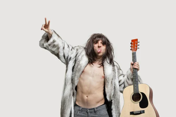 stock image Young man in fur coat holding guitar while gesturing over gray background