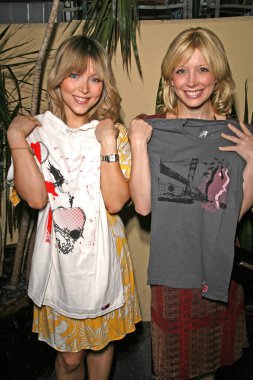 Ashley Peldon ve Courtney Peldon, ellerinde Roger Claude Giyim 'in tişörtleri var.