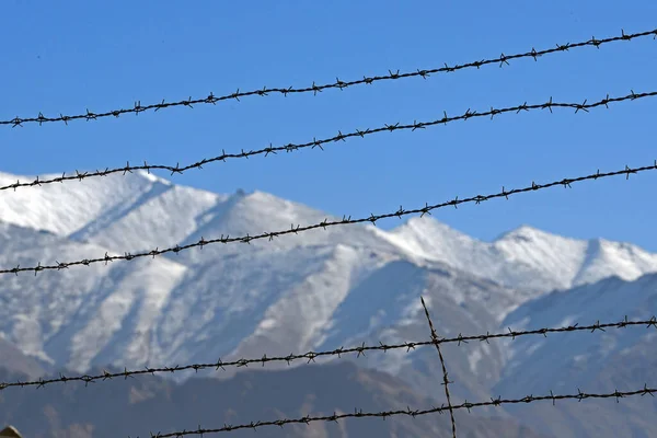 雪の山の背景と冬の有刺鉄線フェンス — ストック写真