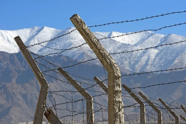 雪の山の背景と冬の有刺鉄線フェンス — ストック写真