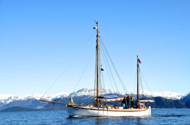 Bu fotoğraf Norveç 'te çekildi. Burada eski bir Colin Archerc yelkenlisini görebilirsiniz. Arka planda Norveç 'in betifule doğasını görebilirsiniz. Dağlar karla kaplı.