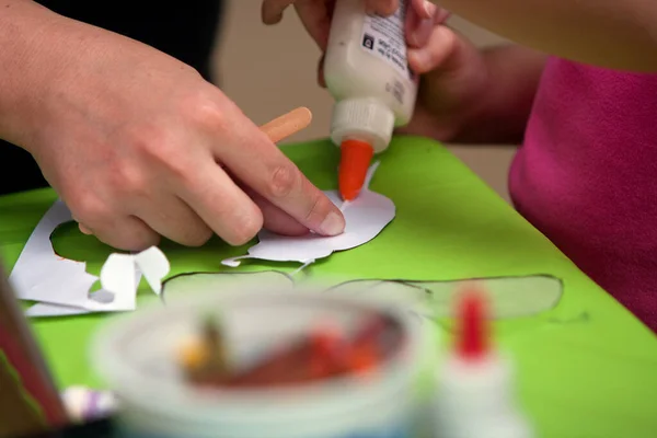 Mother\'s Hand Helps Child Glue Art Project At Summer Festival
