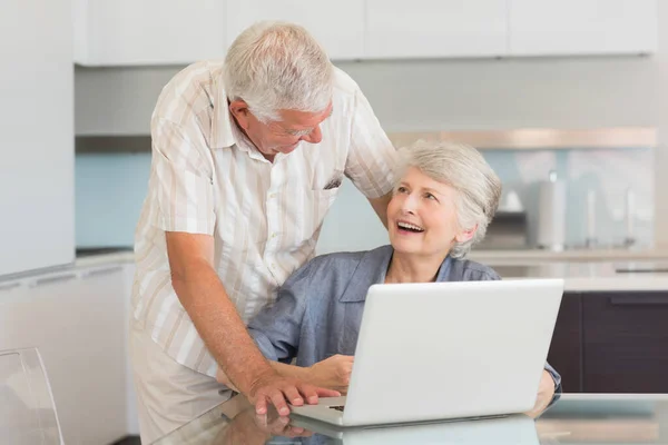 快乐的老夫妇在餐桌边使用笔记本电脑 — 图库照片