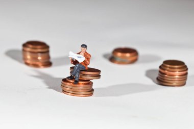 Arka planda madeni paraların üzerinde oturan minyatür insanlar, kapatın.