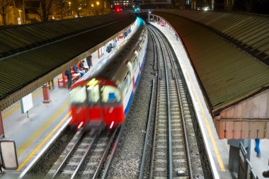 Londra metrosu arka planda insanlar var.