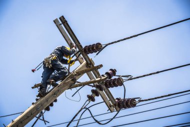 Elektrikçi elektrik direğine asılı