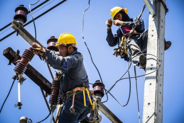 Elektrikçiler elektrik yalıtıcısını değiştirmek için birlikte çalışıyorlar