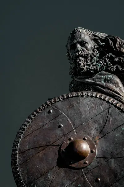 bronze warrior sculpture with shield against sky